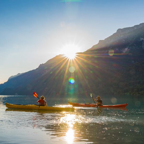 Zwei Männer mit Kajaks unterwegs auf dem Brienzersee während dem Sonnenaufgang