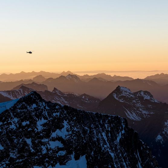 Berge und Helikopter in gelb-oranger Abendstimmung