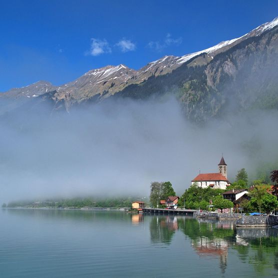 Mystische Nebelschwaden über dem Brienzersee sorgen für eine besondere Stimmung im Dorf Brienz. Die Kirche thront inmitten der Szenerie.