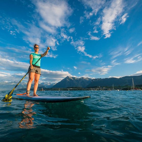 Eine Frau steht auf dem Stand Up Paddle auf dem Thunersee