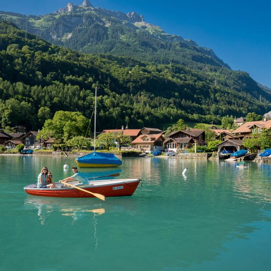 Familie gleitet mit dem Ruderboot in der Bucht bei Iseltwald über den Brienzersee.