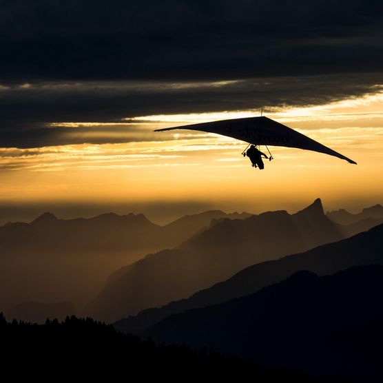 Deltasegler fliegt über den Bergen in der goldenen Abendstimmung